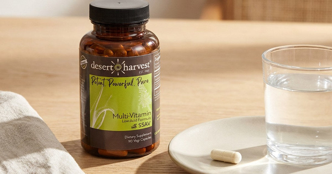 Single Desert Harvest multivitamin capsule beside a glass of water in warm morning light