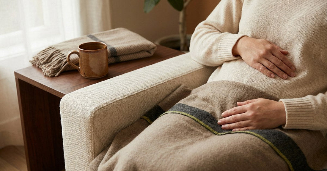 Calm hands resting near the lower abdomen in soft window light, illustrating the gut-brain-bladder connection