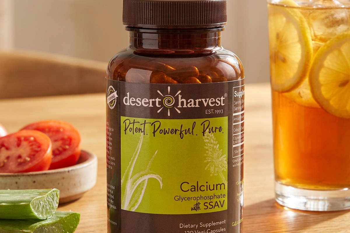 Desert Harvest Calcium Glycerophosphate bottle beside a glass of iced tea and tomatoes