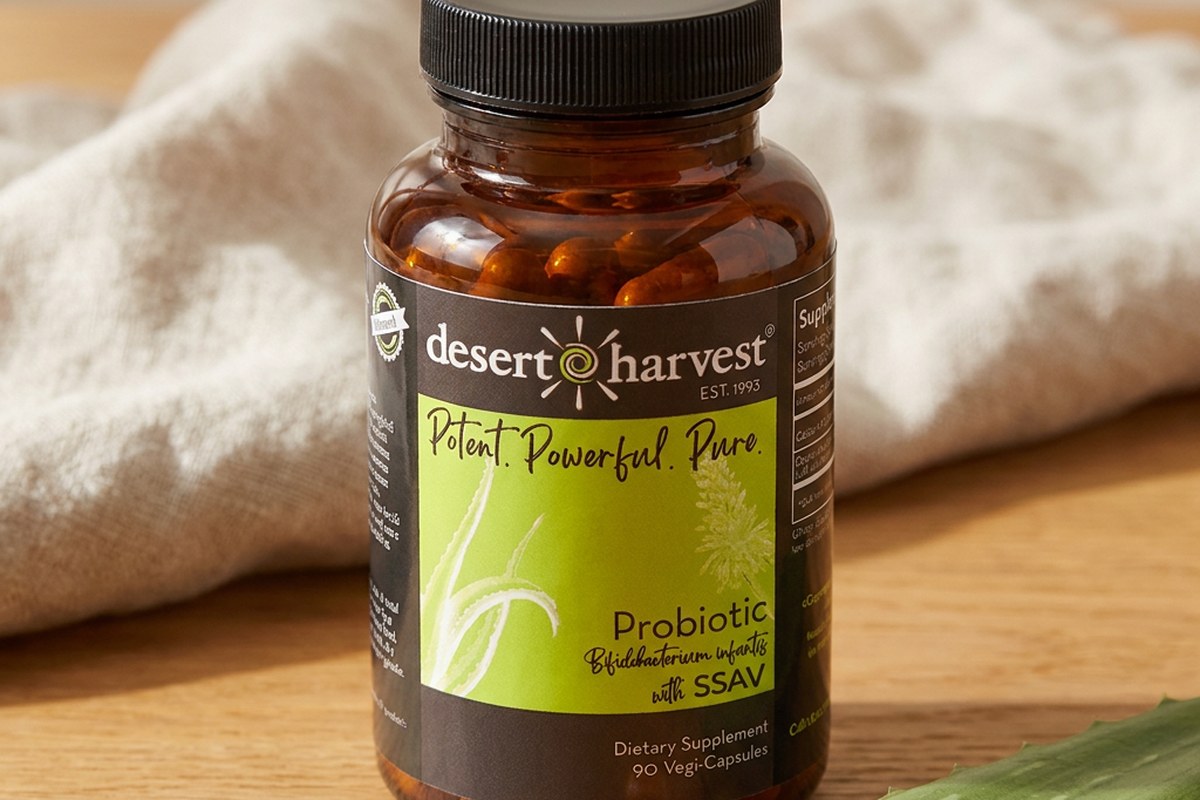 Desert Harvest Probiotic 1 Billion CFU bottle with one capsule and a fresh Aloe Vera segment on wood