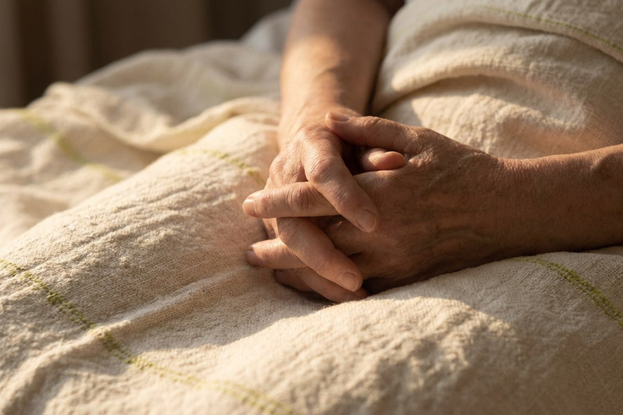 Two hands resting together on a soft blanket
