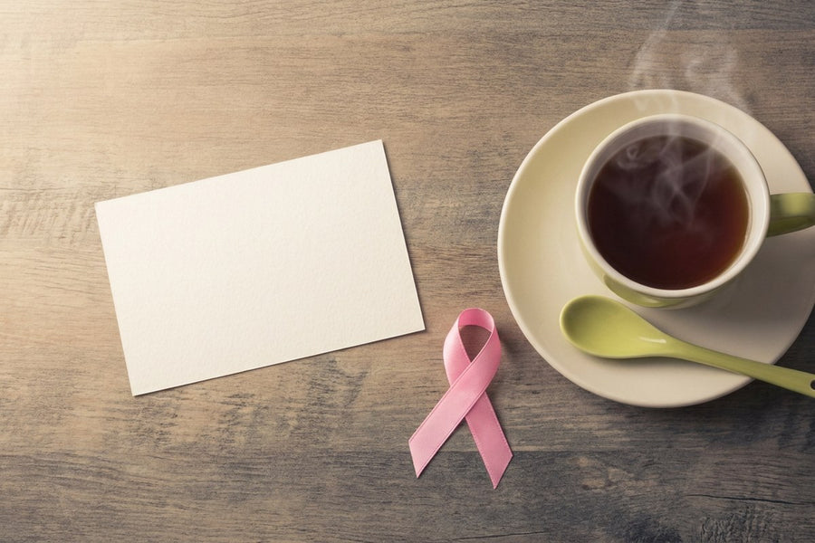 A pink ribbon beside a cup of tea and a blank card